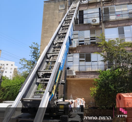 מנוף משאית ליד בניין מגורים עם מזגנים